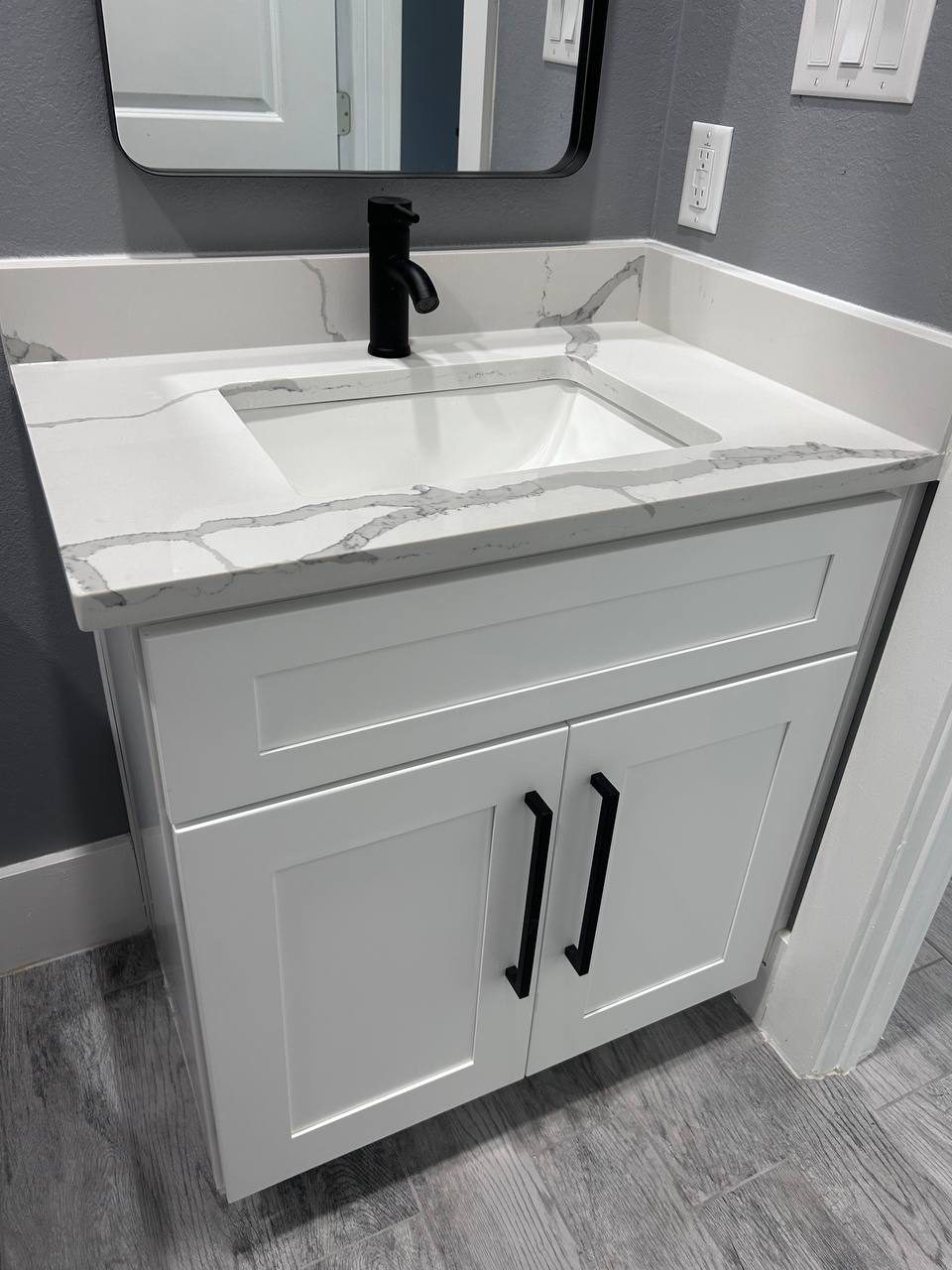 Single vanity with quartz top and black faucet