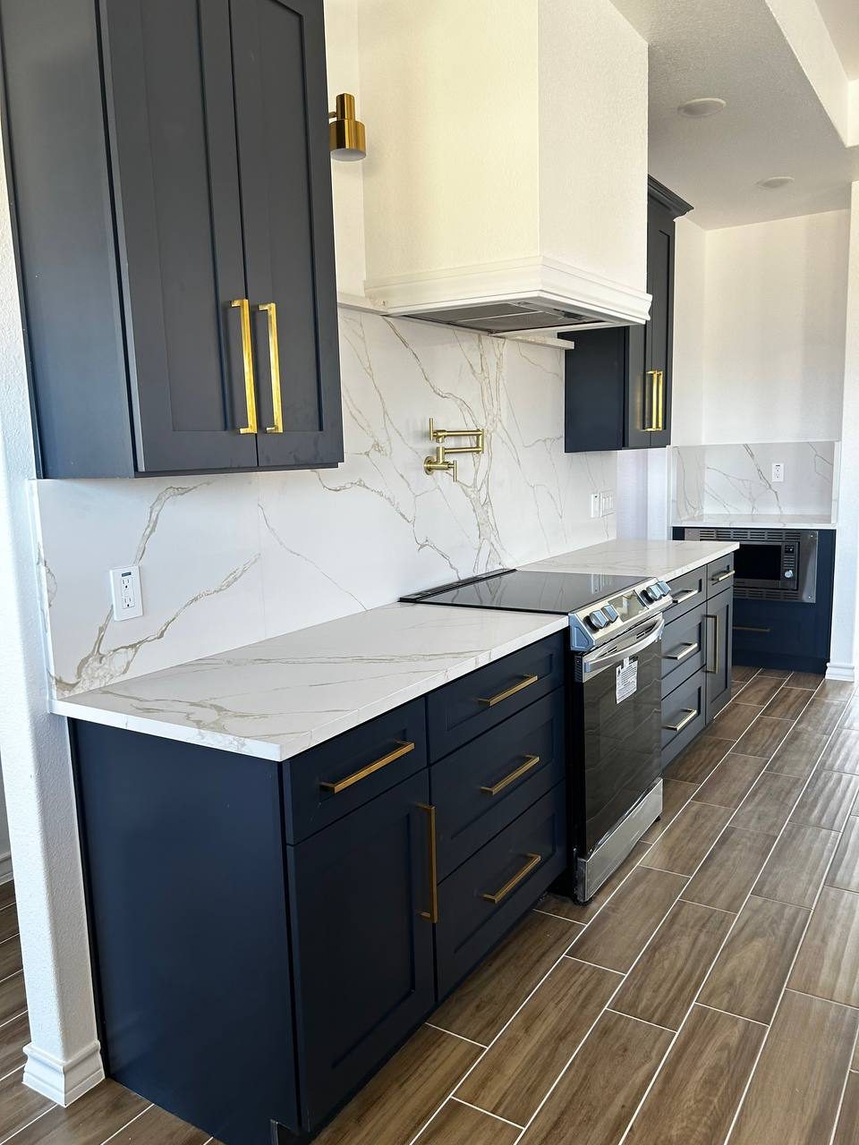 Navy cabinets with gold pulls and stone backsplash