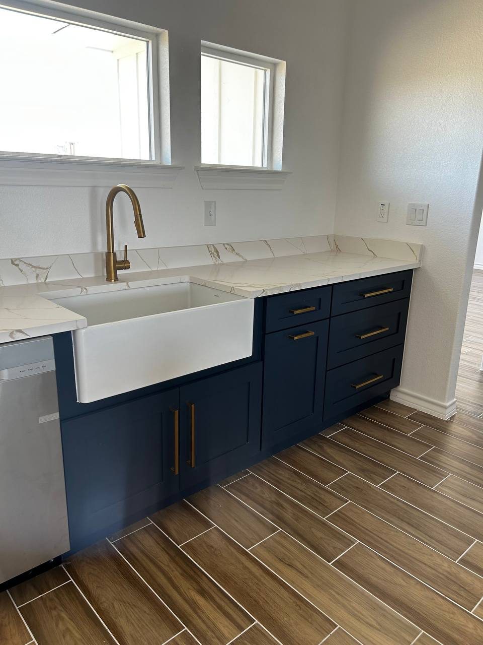 Farmhouse sink in navy cabinetry with gold faucet